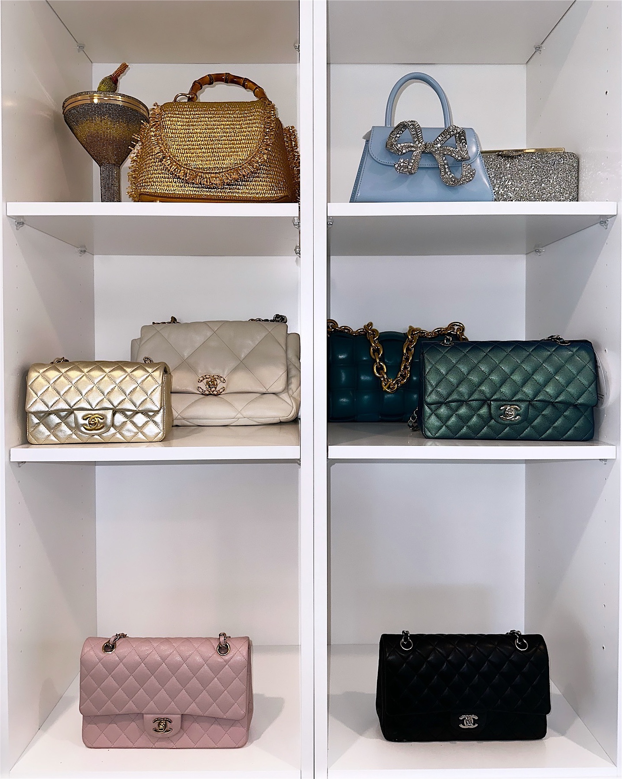 White shelving with handbags displayed one per shelf, spaced and upright